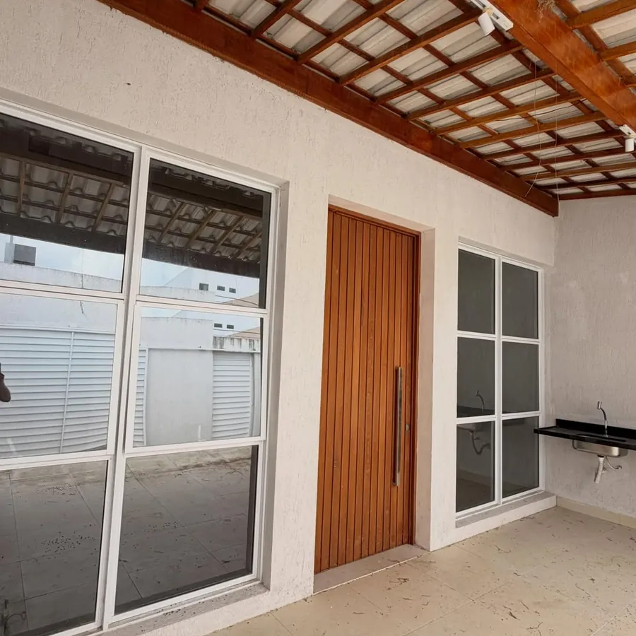 Varanda com porta principal de madeira ripada e bancada de área gourmet
