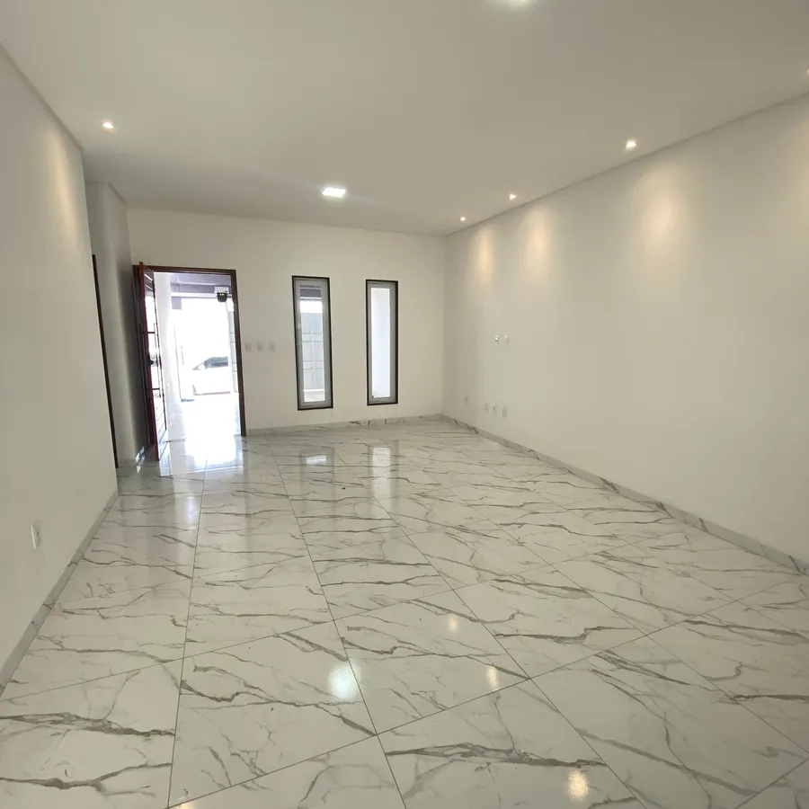 Sala espaçosa com piso em porcelanato marmorizado e iluminação embutida